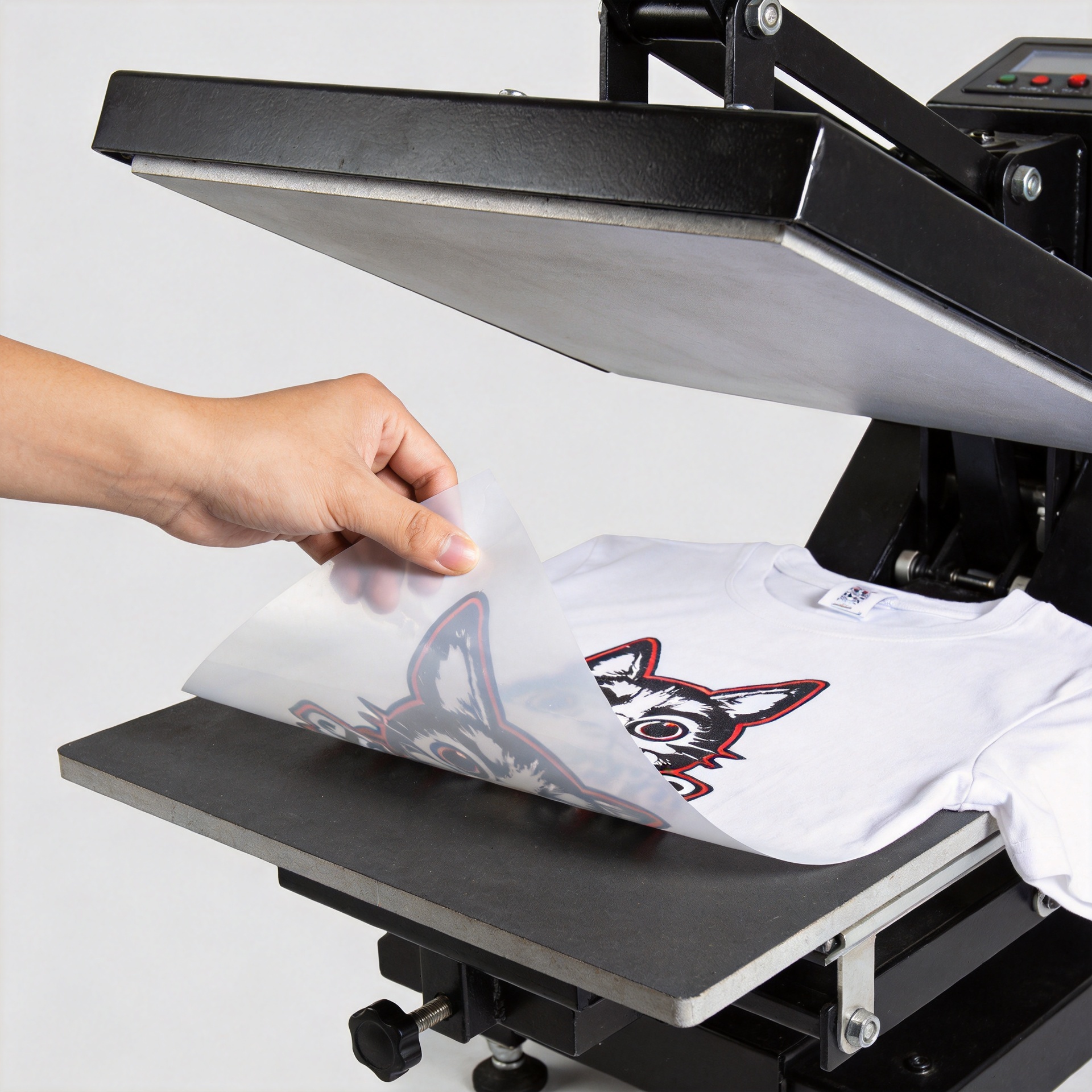 DTF transfer film being peeled from a heat-pressed garment in a professional printing workshop
