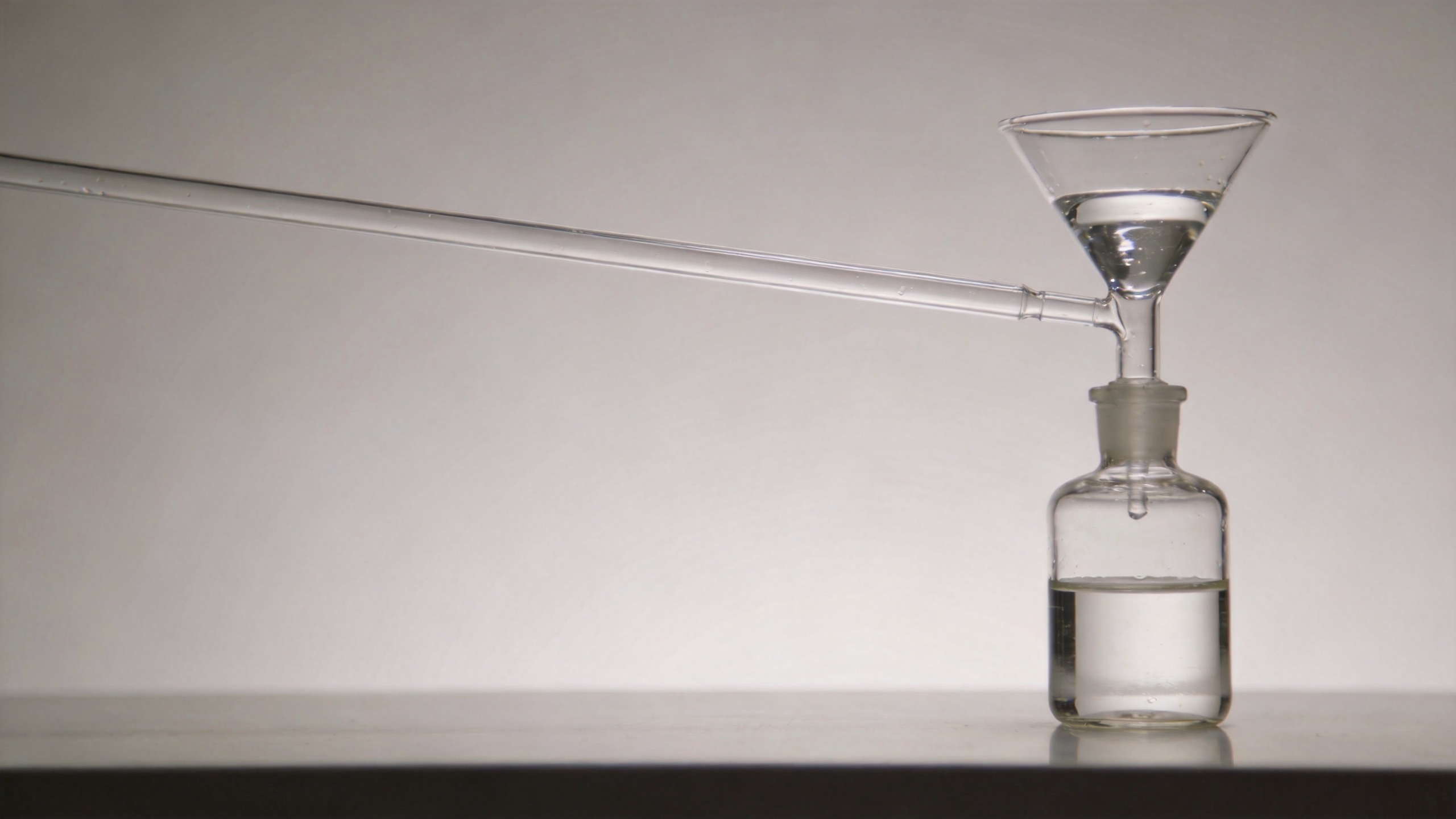 Long stem funnel guiding liquid into a narrow-neck laboratory bottle